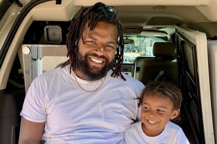 DeMargeo White and his son, Roman, 4, take a break on Thursday, June 6, 2024, from unloading products for White’s business Huey D’s Goodies.