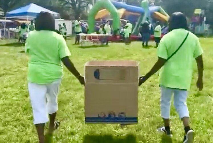 Volunteers carry a box filled with bags of popcorn at last year’s Anti-gun Violence Carnival. Food, games, and rides are free at the event.