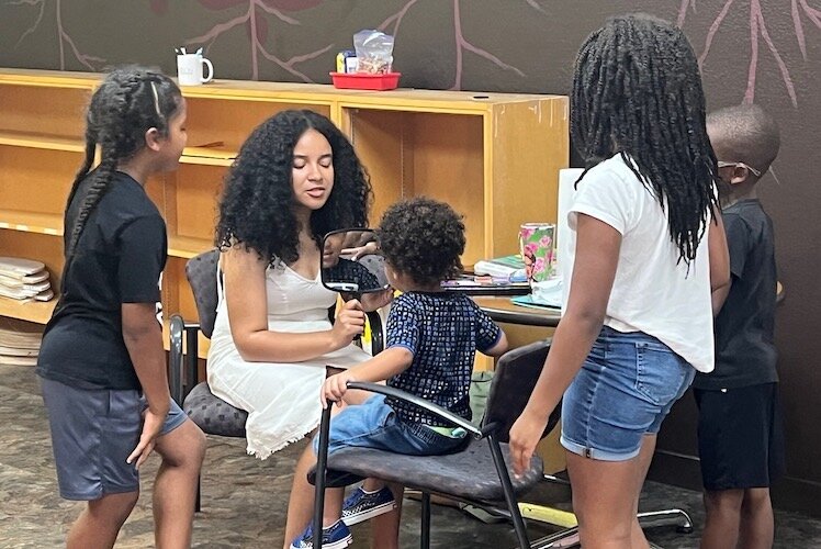 Children’s author Latasha Perry signs one for her books on July 22, 2023, for a girl participating in the meet-the-authors program of Brown Boy Brown Girl Reads.