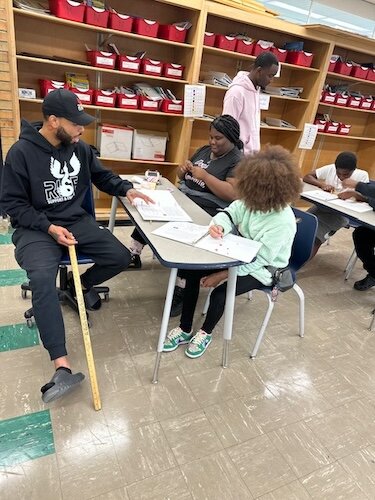 Kaypree Taylor, a R.I.S.E. staff member, works with a youth on their reading skills and assists other youth participants during classroom time.