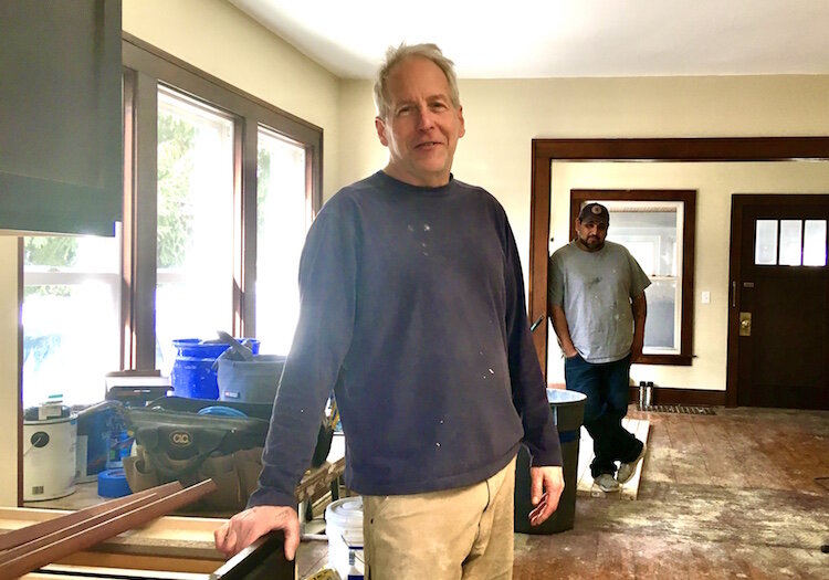 Briggs MacGregor stands inside the Madison Avenue home he is working to renovate. In the background is his friend Jorge Rodriguez, a drywaller who has helped him flip houses over the last 14 years.