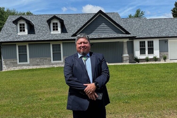 Neil Whitegull, Area Administrator HUD Eastern Woodlands Office, stands in front of one of four new houses that are part of Phase 9 of the NHBP's ongoing housing initiative.