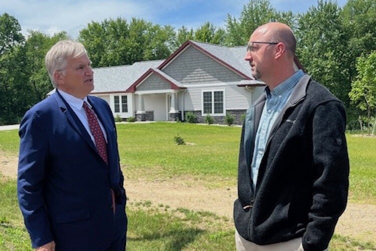 Richard Monocchio, Principal Deputy Assistant Secretary, Office of Public and Indian Housing, at left, speaks with Dan Green, Chief Planning Officer, at right, in front of one of four new homes completed as part of Phase 9 of the NHBP's housing initi