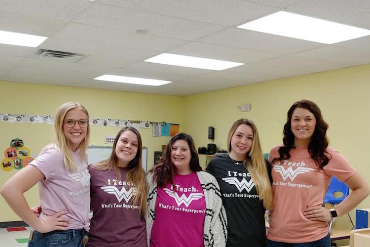 Learning Zone staff members wear matching shirts saying "I teach, whats your super power?" 