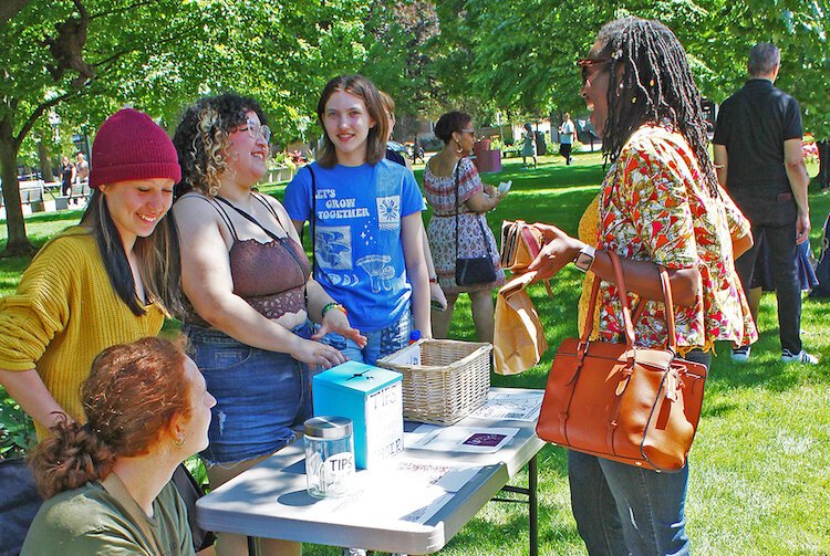 Students soliciting donations during “Lunchtime Live!” in Kalamazoo’s Bronson Park on June 14 chat with a woman who contributed. From the left are Astrid Westbury, Aubry Walker, Sappho Slate, and Evangeline Fraley-Burgett.