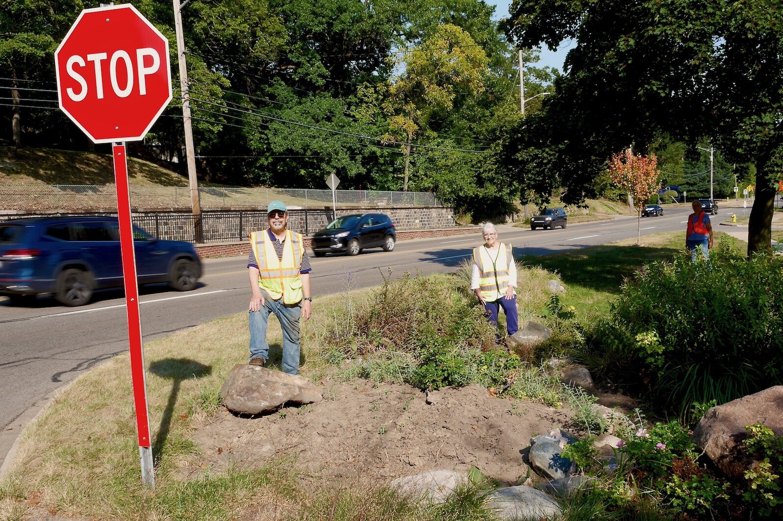 Rob and Claire Milne in their safety vests at their rock garden which has stopped a few wayward cars over the years from going further.