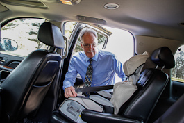 Driver Ken Moody places a child seat.