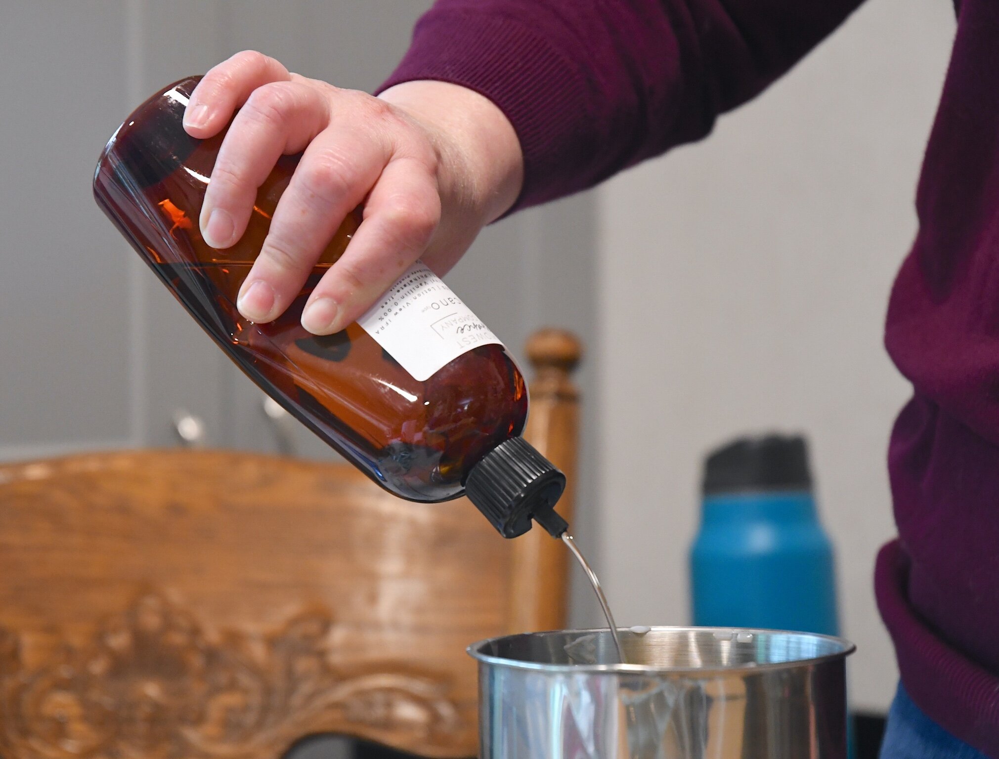 Kellee VanValkenburg adds scent to melted soy wax in a container.