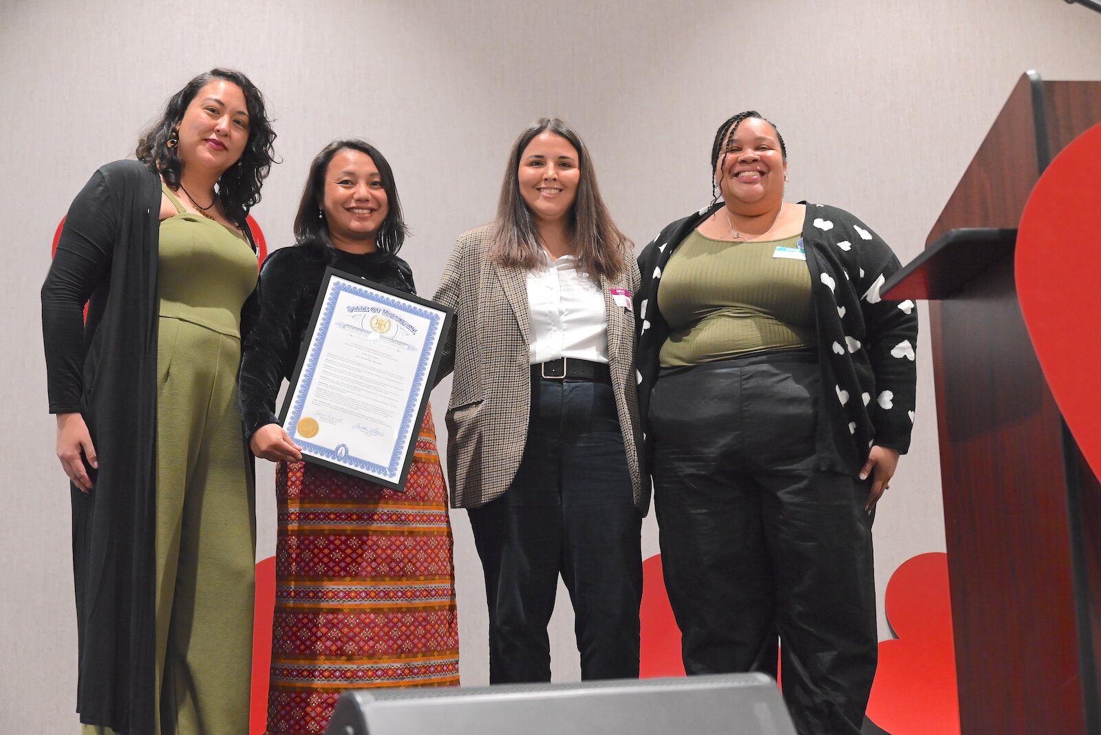 Anna Cool, third from left, representing Michigan Governor Gretchen Whitmer, poses with Elizabeth Garcia, Tha Par, holding a proclamation from the governor, and Frances Vicioso during Battle Creek Truth, Racial Healing, and Transformation’s (BCTRHT) 