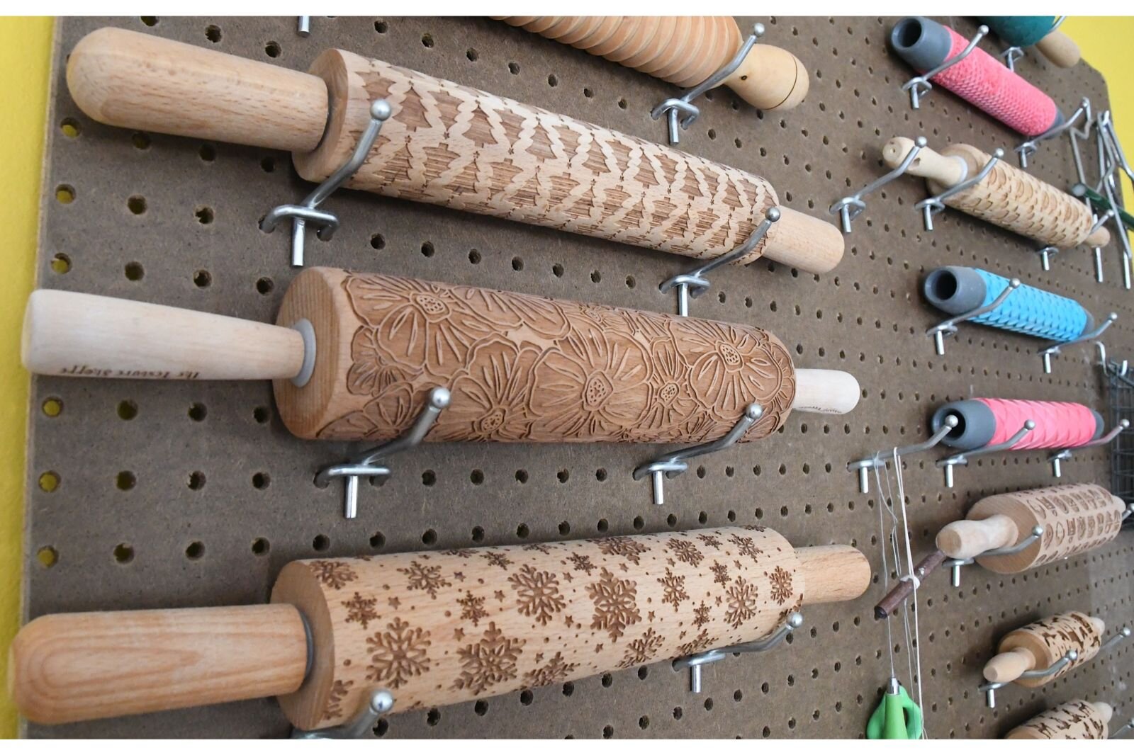 Laura uses a variety of rolling pins to make designs on clay.