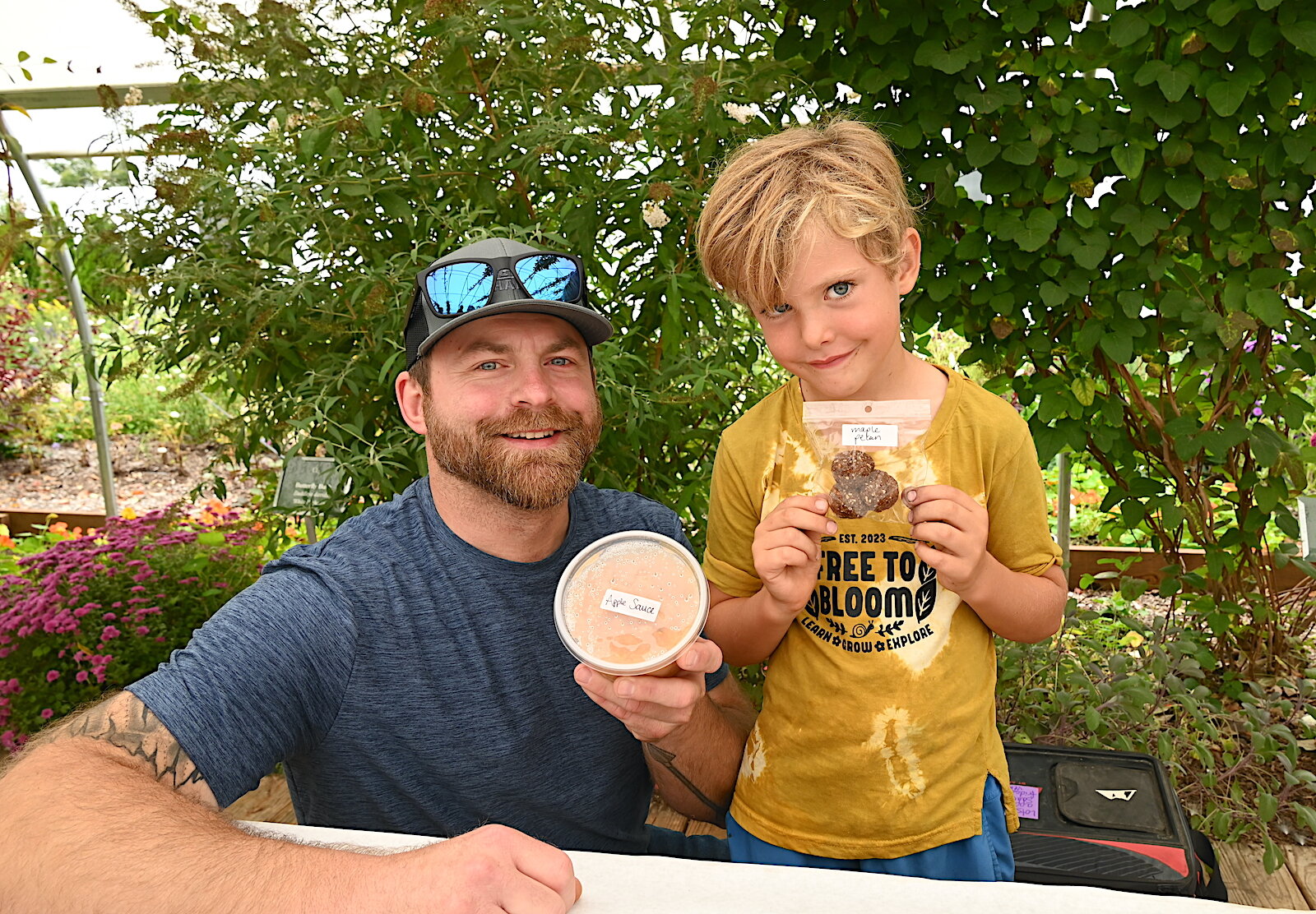 Mike McKim and his son Graham hold up items for sale to benefit the Free To Bloom home school collective during Of The Land’s harvest festival.