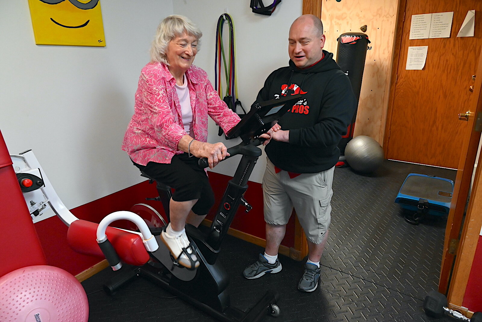 Troy Huggett works with his mother Shirley Huggett on a cycling machine.