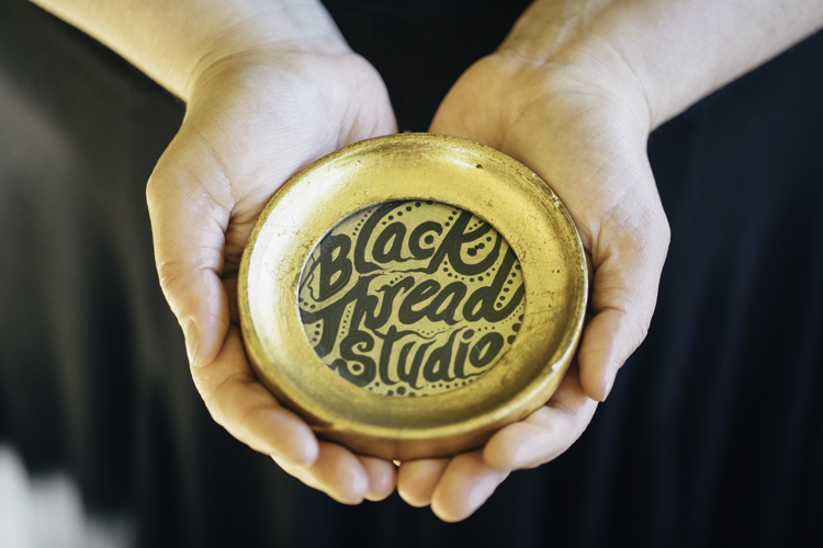 Eana Apple Agopian holds a symbol of her Black Thread Studio in her hands.