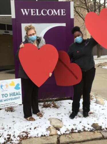 Employees at Summit Pointe hold up hearts at the Race to Heal yard sign.