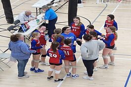 Andrea Huizar (middle in blue) coaching a volleyball team.