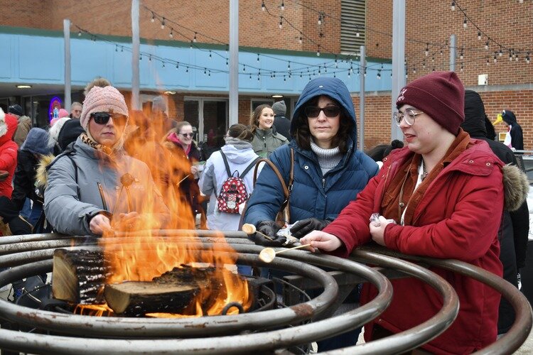 Keeping warm by the fire, attendees roast smore's.