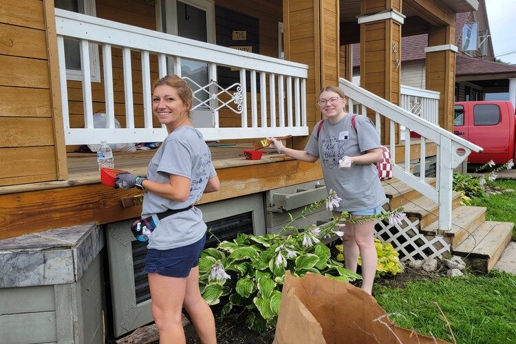 Volunteers staining a porch at the 2023 Rock the Block event.