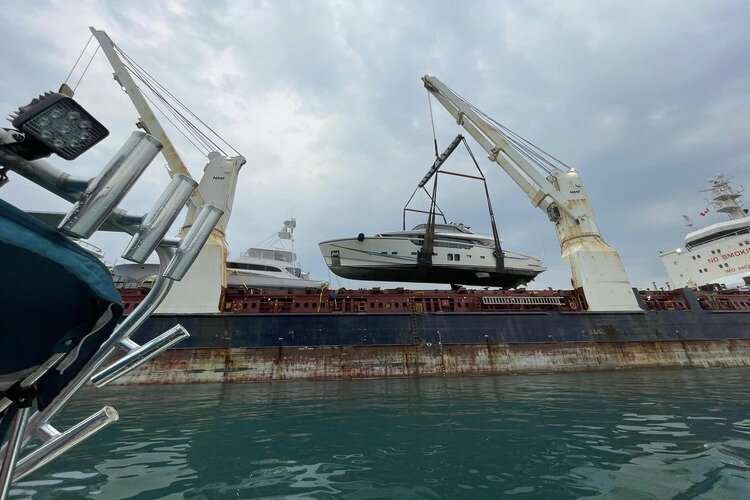 Transporting a yacht on a freighter, loading and offloading the vessel requires a sling and crane.