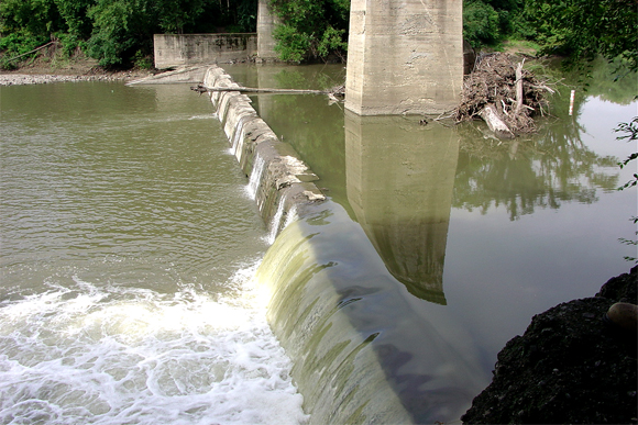 Water flows over a small dam. 