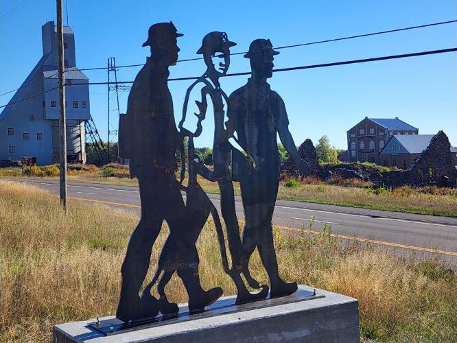 A statue depicting three Italian immigrants heading to work in the Quincy Mine overlooks the shafthouse and hoist house.