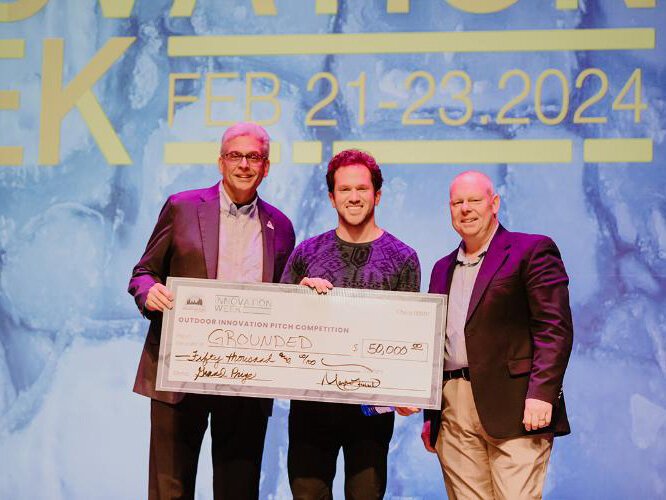 Sam Shapiro, center, receives his check from the Outdoor Innovation Pitch.